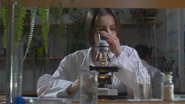 Young scientist looking through a microscope in a laboratory. Young scientist doing some research.