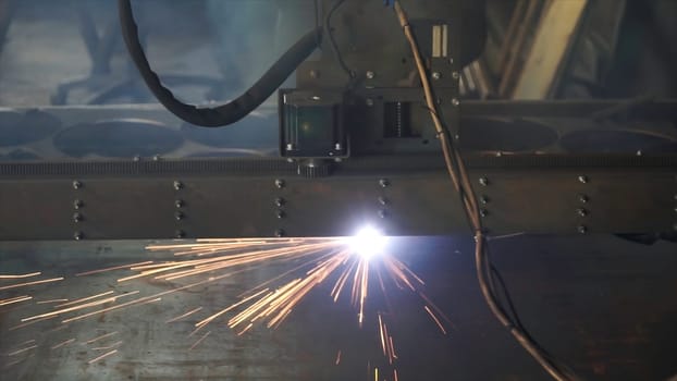 Cutting of metal. Sparks fly from laser. Cut sheet metal at workshop. Modern tool in heavy industry. High precision CNC laser cutting metal sheet and metal pipe in factory. Laser cutting of flat sheet metal steel material with sparks.