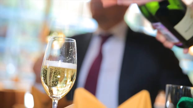 Pour the champagne into a glass. Bartender pouring champagne into glass, close-up. Champagne pouring in glass HD
