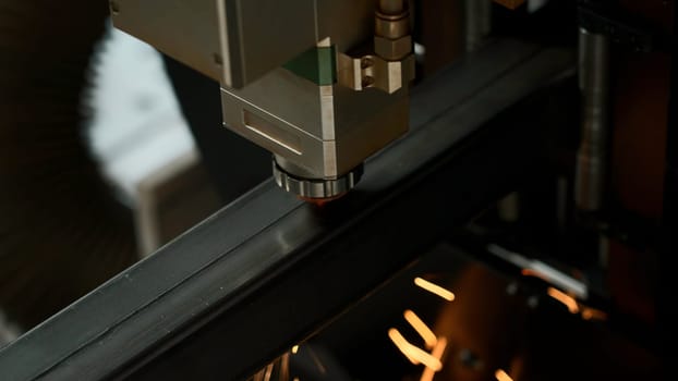 Laser cut head machine while cutting the sheet metal with the sparking light in factory. Creative. Process of laser engraving on metal