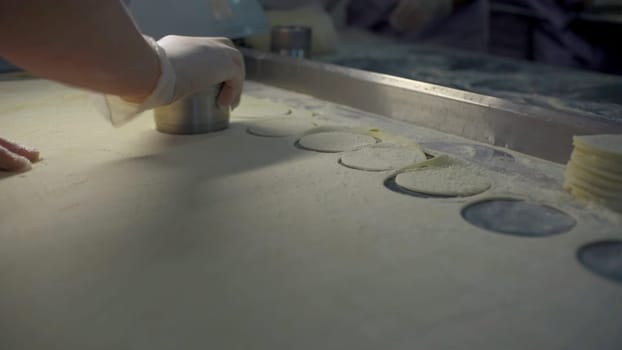 Close-up of slicing dough for dumplings. Clip. Cook quickly makes dumpling molds. Round cutting of dough for large number of dumplings.