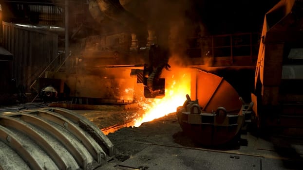 Molten iron flowing in a steel mill with many sparcles flying into the sides. Hot shop of the steelmaking factory with professional machinery.