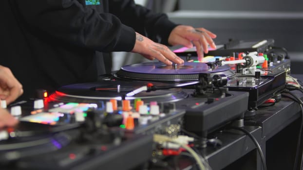 DJ spinning record at disco. Art. Close-up of DJ's hand on mixer. Glowing music panel at party. Musician's work in nightclub.