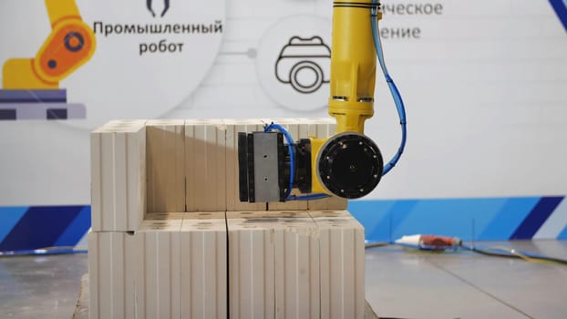 Details of modern technologies and robots exhibition in construction industry. Automated hand of a robot constracting a wall from heavy blocks.