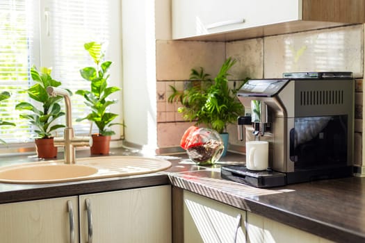 Modern electric coffee machine with cup on countertop in kitchen.