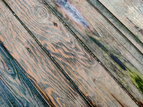 Surface of wooden boards with multicolored spots from dampness, diagonal lines, top view.