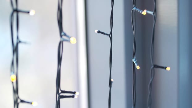 Beautiful garland with lights close up. selective focus of Christmas warm gold garland lights. Christmas lights on window background.