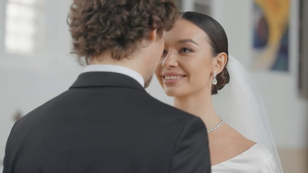 Beautiful newlyweds in church. Action. Elegant couple of newlyweds walk down aisle. Beautiful newlyweds at wedding ceremony in church.