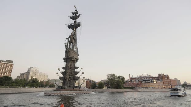 Bronze sculpture on a granite pedestal, located in Petrovsky Square of Voronezh.Action. A landscape shot while sailing on the river next to a small ship at the back of the house and beautiful foggy clouds
