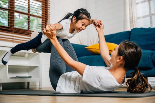 In the comfort of their home a mother and her daughter practice yoga with the little bird posture strengthening their bond and creating a joyful and harmonious family moment of trust and happiness.