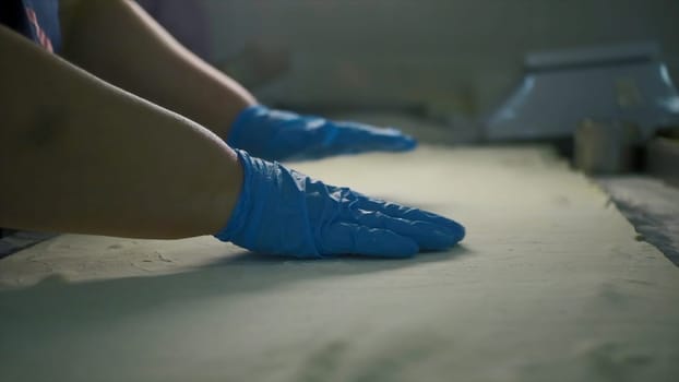 Close-up of cook cooking with thin dough. Clip. Thin large dough for cooking. Woman stretches thin dough. Industrial bakery.