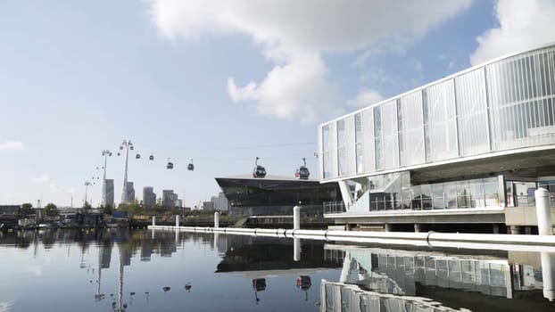 Modern funicular with moving cabins, time lapse effect. Summer landscape with glass facade cable car station on blue cloudy sky background.