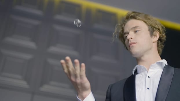 Groom throws wedding rings. Action. Attractive groom in suit throws rings and catches them. Groom is playing with wedding rings in anticipation.
