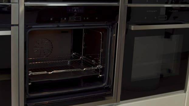 Close up of man unlocking and opening new modern mini oven for kitchen in furniture shop. Presentation of a new oven model, high tech concept.