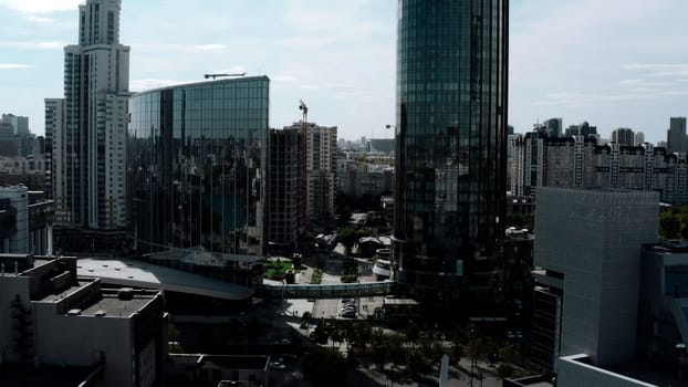 Summer landscape on a built-up city from a height. Stock footage. High-rise beautiful glass offices standing on the banks of the river and green parks for walking and a visible road for traffic. High quality 4k footage