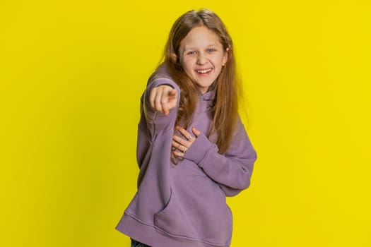 Happy young preteen child girl kid laughing out loud after hearing ridiculous anecdote, reaction on funny joke, feeling carefree amused. Positive people lifestyle. Children on studio yellow background