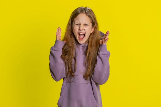 Irritated angry preteen child girl kid scream from stress tension problems feels horror hopelessness fear surprise shock expresses rage nervous quarrel. Teenager children isolated on yellow background