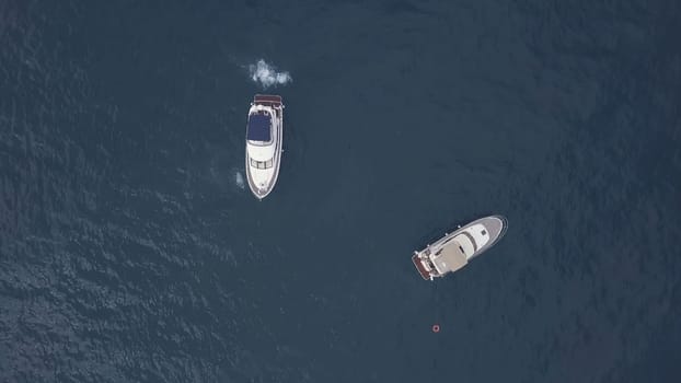 Amazing aerial top view of two yachts and swimming friends in dark blue water. People having fun in caribbean paradise sea near new sailing boats.
