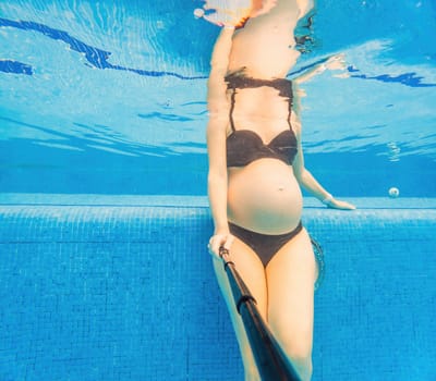 Embracing aquatic fitness, a pregnant woman demonstrates strength and serenity in underwater aerobics, creating a serene and empowering image in the pool.