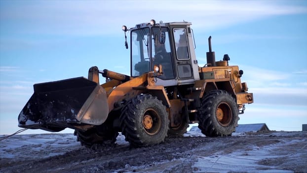 Snowy weather, excavator digging frozen ground. Clip. Heavy industry concept, machine at mine work on blue sky background