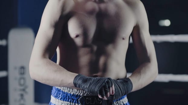 Closeup of a mixed martial arts fighter wrapping his hands before a fight. Boxer wraps his hand a red bandage before the figh.