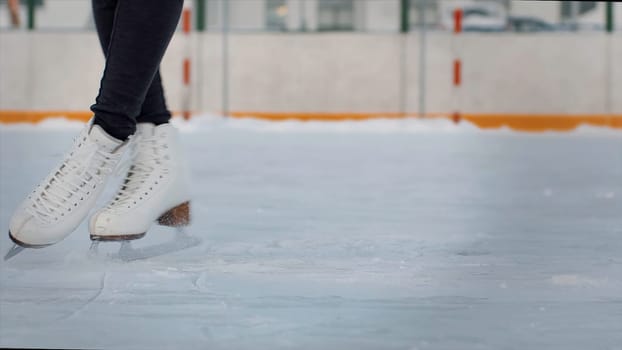 Professional female ice figure skater practicing spinning on outdoor skating rink. Video. Woman ice dancing surrounded by residential high rise houses