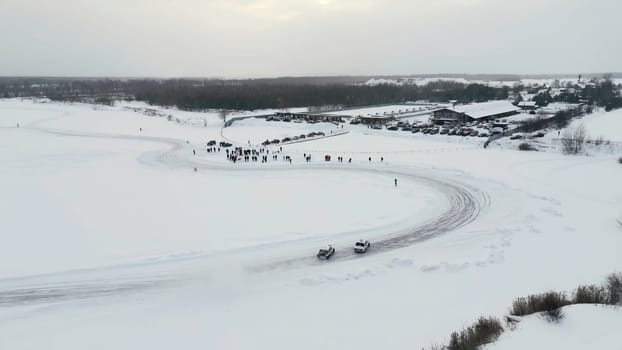 Slow motion of a racing cars championship sliding on an ice track. Clip. Winter drift competitions, aerial view
