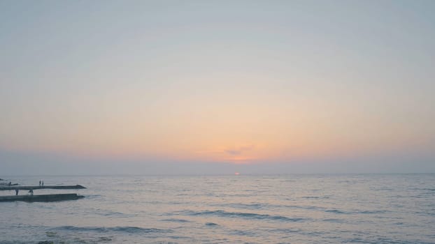 Beautiful waves on beach at sunset. Action. Waves of clear water roll on rocky beach on background of sunset. Beautiful seascape at sunset.