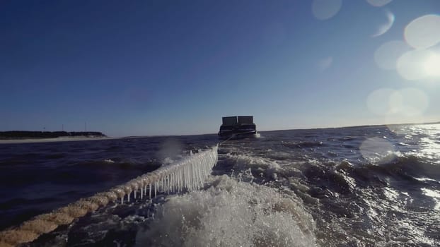 Large barge at the North Pole. CLIP. In the foreground Rope with icicles. In the background, a heavy barge in ice water is in focus. A ship pulling a barge in tow.