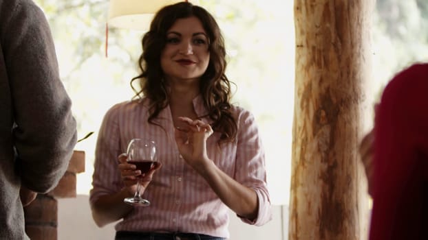 Beautiful young brunette woman with curly hair enjoying party flirting with someone, drinking wine. Media. Woman with a glass of red wine