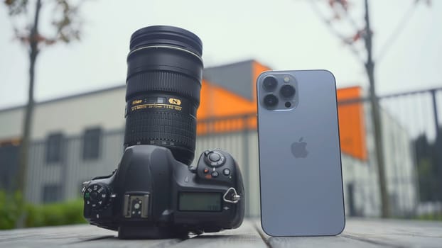 RUSSIA, MOSCOW - SEPTEMBER 27, 2021: Camera and phone comparison. Action. Professional camera with lens or new iPhone. Comparison of cameras of new iPhone 13 pro with professional camera.