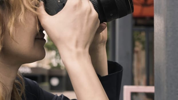 Close-up of beautiful woman taking pictures with professional camera. Action. Woman photographer talks and takes photos with camera.
