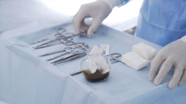 Close-up of surgeon preparing instruments for surgery. Action. Professional surgeon prepared various types of clips and scissors for complex operation.