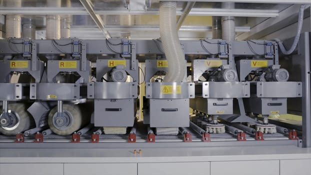 Industrial machines with rotating bristles. Action. Rotating bristly nozzles of different sizes read and paint wooden boards in industrial enterprise.