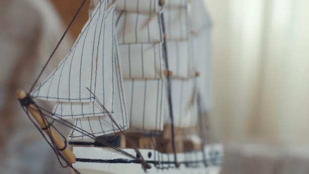 Close-up of the little marine white ship model from the wood on a striped background on the blurred light background. Hobby and collecting concept