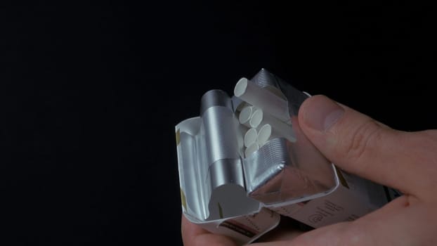 Man's hand pulling up a sigarette from box. Get sigarette from pack closeup. Closeup of a man pulling a nail out of a pack of cigarettes. Box of cigarettes. Hand takes a cigarette out of pack 4K