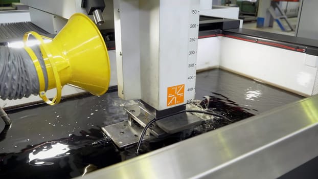 Metal cutting under water at factory. Scene. Processing of steel part that is cooled by water and fan unit at enterprise. Underwater metal cutting method.