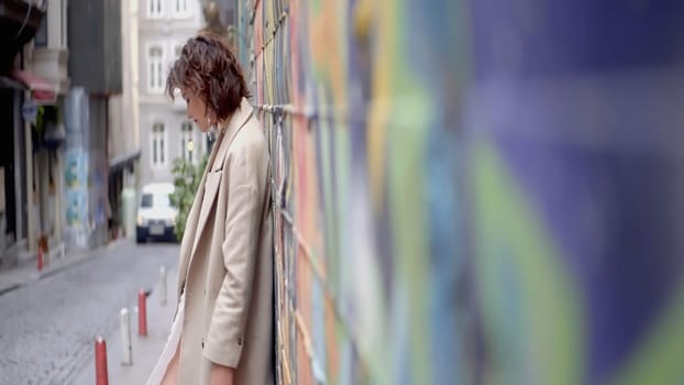 Beautiful portraits next to the graffiti wall. Action.Stylish people participating in street art shooting with a wall with bright graffiti. High quality 4k footage