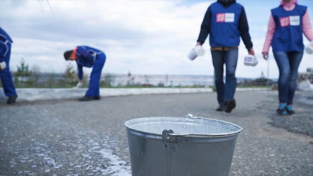 Workers in blue are ready to work for the city in outdoor. Clip. Closeup of a worker. Workers in blue dip the brush in the paint.