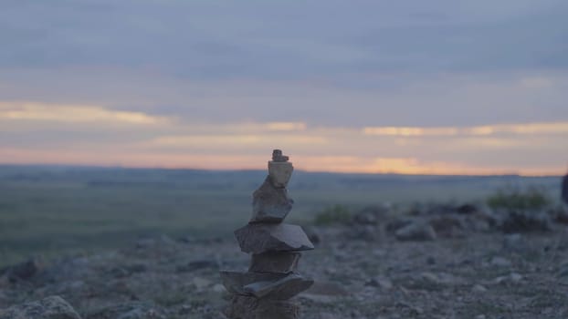 Pebbles tower Zen and balance. Stack of the pebbles against the sky. Tower of stones on the background of the field and the morning sky.