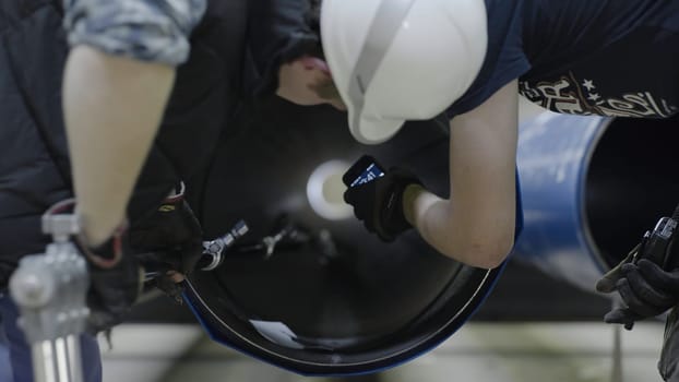 Working on tubular production. Men look inside the pipe.