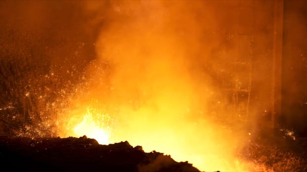 Close up of liquid metal in hot workshop of the metallurgical plant. Flying sparkles inside the furnace, heavy industry concept.
