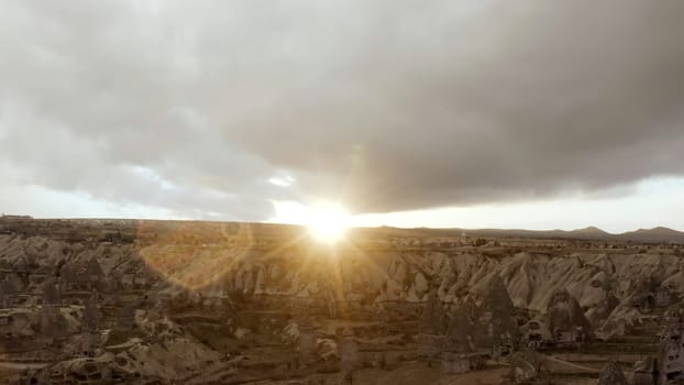 Grey landscape from a bird 's - eye view . Action . The bright sun is shining directly into the camera and a deserted forest with mountains is visible. High quality 4k footage