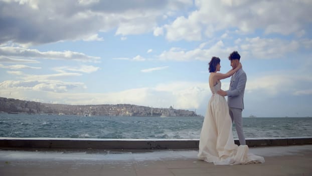 Young and beautiful wedding couple in front of a river. Action. Hugging bride and groom outdoors at the embankment