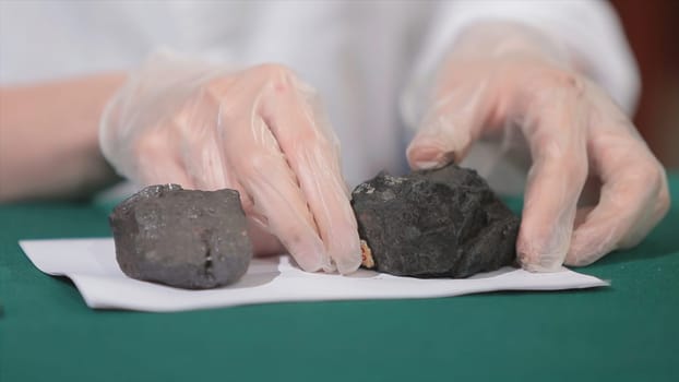 Male hands in gloves holding coal. Scientist with a sample of coal. Black coal in miner's hand.