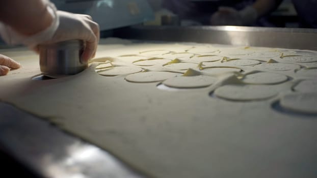 Close up of a hand in glove making flat circles of dough. Clip. Process of dumplings production at the factory