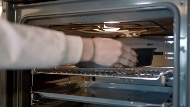 The concept of cooking. Action. A heated stove into which a frying pan with a dish is pushed. High quality 4k footage