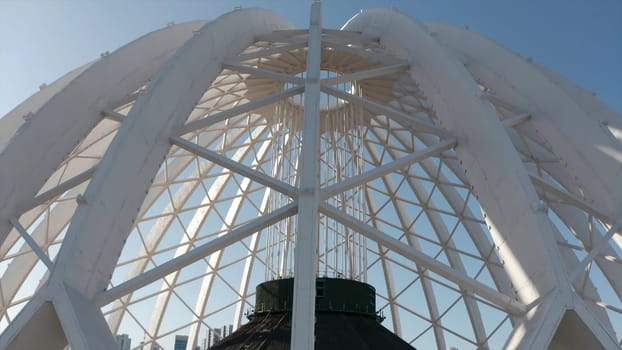 Beautiful domed structure. Stock footage. White air beams in dome structure. Top view of domed circus building on background blue sky.