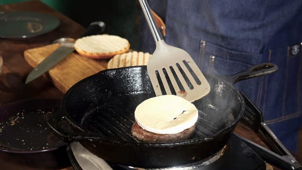 Preparing beef cutlet with cheese on the grill for burgers. Stock footage. Chef prepares a cutlet for a hamburger with cheese.
