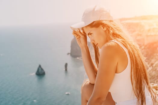 Woman travel sea. Young Happy woman in a long red dress posing on a beach near the sea on background of volcanic rocks, like in Iceland, sharing travel adventure journey